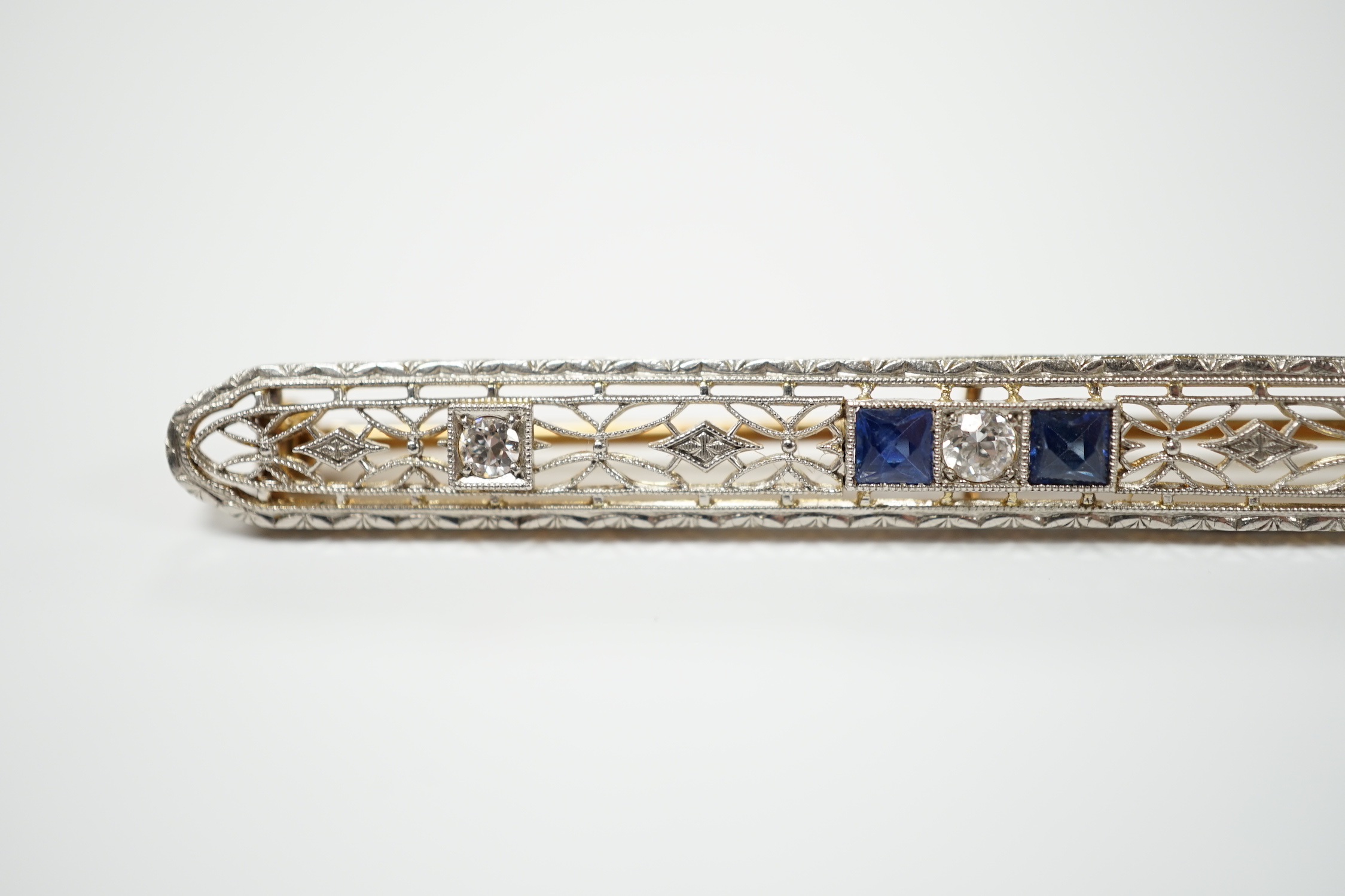 A Belle Époque style pierced 14k, sapphire and diamond cluster set bar brooch, 70mm, gross weight 5.5 grams.